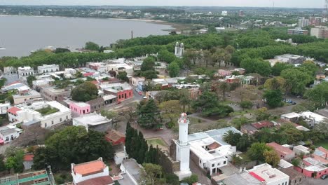 Scenic-View-Of-Ancient-Lighthouse-In-A-Small-Town-In-Colonia-Del-Sacramento,-Uruguay---aerial-pullback