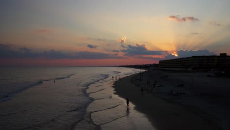 God-rays-shine-through-dusky-clouds-at-sunset-on-Folly-Beach,-South-Carolina