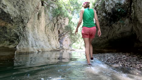 Summer-adventure-concept:-woman-walks-in-the-water,-in-a-gorge-between-rocks