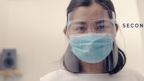 Slow-motion-close-up-of-Asian-woman-in-protective-face-mask-and-opens-eyes-looking-straight-at-the-camera-with-text-Second-wave-COVID-19