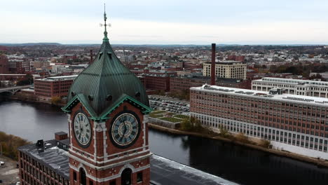 Ayer-Mill-Clock-Tower-In-Lawrence,-Massachusetts-Overlooking-Merrimack-River-And-Bridge-At-Daytime---aerial-close-up,-orbiting-shot