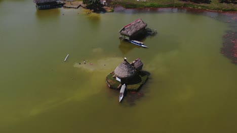 4k-Daytime-aerial-drone-video-looking-at-a-small-house-built-over-the-water-with-a-boat-parked-in-at-Laguna-de-los-Milagros-,-Tingo-Maria,-Peru