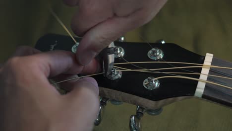 Person-Cutting-Off-Excess-Strings-From-The-Tuning-Heads-Of-An-Acoustic-Guitar-Using-A-Pliers
