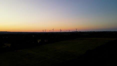 Aerial-shot---flying-up-and-straight-towards-Puck-wind-farm-on-sunset,-rotating-wind-turbines-silhouette-on-orange-sky-background,-Pomorskie,-Poland