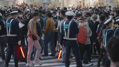 Policías-Con-Máscaras-Mientras-Controlan-A-La-Multitud-En-El-Cruce-De-Shibuya-En-La-Noche-De-Halloween-En-Tokio,-Japón---Tiro-Completo,-Cámara-Lenta