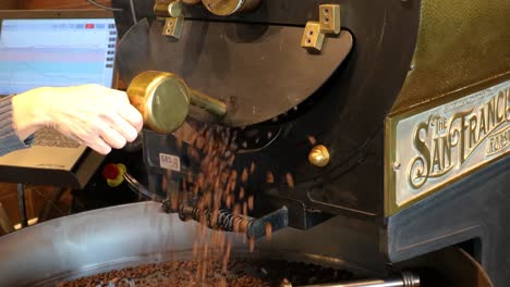 Woman's-hand-opening-the-dryer-door-of-a-commercial-coffee-roaster