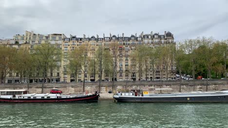 Una-Vista-Lateral-De-Los-Edificios-Al-Lado-Del-Río-Sena-Mientras-Toma-Un-Paseo-En-Barco-Turístico-En-París,-Francia