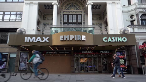 A-slow-motion-shot-of-people-cycling-and-walking-past-the-boarded-up-Empire-Imax-Cinema-on-Leicester-Square-during-the-second-national-Coronavirus-lockdown