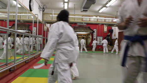 Kinder-Im-Karate-Unterricht-Laufen-Herum,-Um-Sich-Aufzuwärmen,-Drinnen,-Im-Kreis,-Weiße-Uniformen