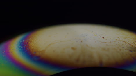 Makroaufnahme-Einer-Seifenblase-Mit-Regenbogenfarbenen-Streifen-Am-Rand-Der-Stange