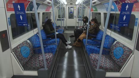 Drei-Frauen-Sitzen-In-Der-Londoner-U-Bahn-Und-Tragen-Gesichtsmasken-Und-Soziale-Distanzierung