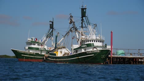 Einspielung,-Malerischer-Blick-Auf-Wellen-Auf-Dem-Blauen-Meer-An-Einem-Sonnigen-Tag-In-Adolfo-Lopez-Mateos-Baja-California-Sur,-Mexiko,-Zwei-Fischerboote,-Die-An-Den-Docks-Im-Hintergrund-Geparkt-Sind