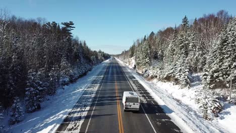 Van-Fährt-Durch-Kalten,-Sonnigen,-Blauen-Himmel-Wintertag-In-Der-Nördlichen-Landschaft-Kanadas---Drohne-4k-Antenne