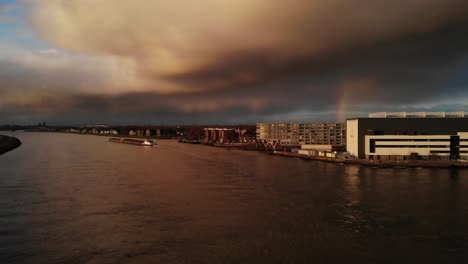 Dramatischer-Himmel-über-Dem-Noord-River,-Während-Ein-Langes-Containerschiff-Den-Fluss-Hinunter-Segelt