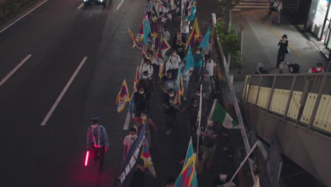 Manifestantes-Asiáticos-Con-Máscaras-Y-Banderas-Ondeando-Mientras-Marchan-Por-La-Calle-En-Tokio,-Japón-Por-La-Noche---Solidaridad-Con-La-Protesta-De-Hong-Kong---ángulo-Alto,-Tiro-Estático