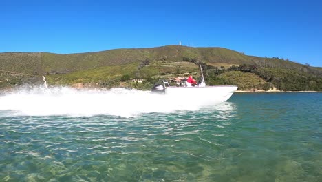 Tracking-shot-as-white-speed-boat-makes-tight-turn-on-blue-sky-lagoon