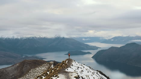 Hiker-at-the-end-of-a-ridge-line-atop-Roys-Peak-in-New-Zealand-taking-photos-and-looking-at-view