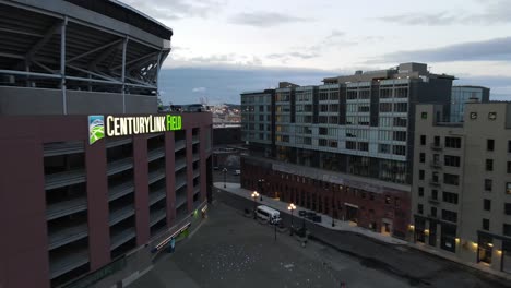 Early-morning-reveal-of-the-north-corner-of-Century-Link-Field,-empty-parking-lot,-aerial-dolly-zoom