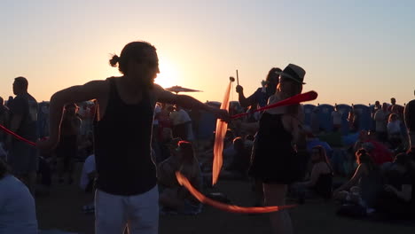A-Group-of-Performers-Put-on-a-Show-with-Poi-Ribbons-and-Devil-Sticks-During-Sunset-at-a-Large-Festival