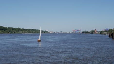 Sail-boat-cruises-on-Elbe-River-in-Hamburg-at-sunny-day