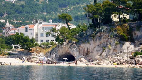 Wide-shot-of-tourists-enjoying-the-beach-near-a-cave-in-Makarska-Croatia