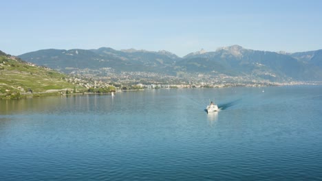 Flying-in-reverse-over-Lake-Léman-with-Belle-Epoque-steam-boat,-Vevey,-Montreux-and-the-Alps-in-the-background---Switzerland