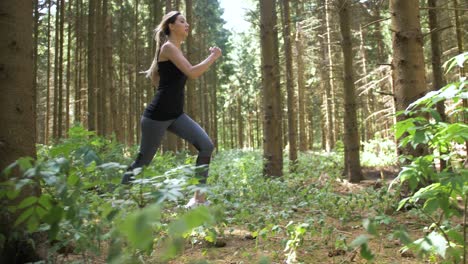 Woman-begins-running-through-wooded-area-with-long-prancing-stride