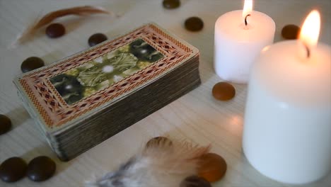 background-with-mystic-cards-deck-near-candles-with-flickering-flames,-stones-and-feathers