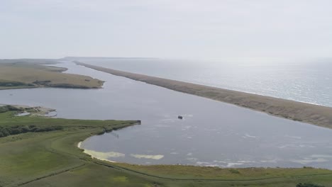Aerial-tracking-from-right-to-left-along-Chesil-Beach-and-the-fleet-lagoon-rotating-the-shot-out-to-sea-and-the-oncoming-sunshine