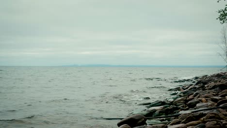 Lake-Superior-Wellen,-Die-Ins-Ufer-Rollen,-Mit-Fernen-Bergen-Am-Horizont