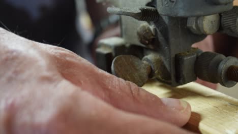 Close-up-of-a-man-cutting-a-block-of-wood-with-a-bandsaw