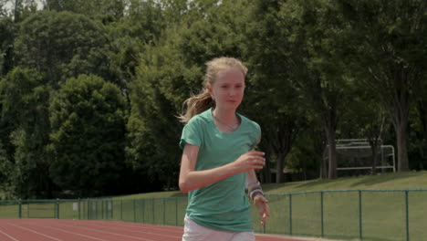 Teen-girl-athlete-runs-track-towards-and-past-camera-in-slow-motion
