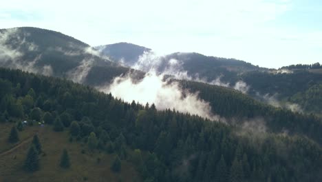 Disparo-Aéreo-De-Drones-Tirando-Hacia-Atrás,-Revelando-La-Niebla-Del-Valle-En-Movimiento-En-La-Ladera-De-Una-Montaña-Rumana
