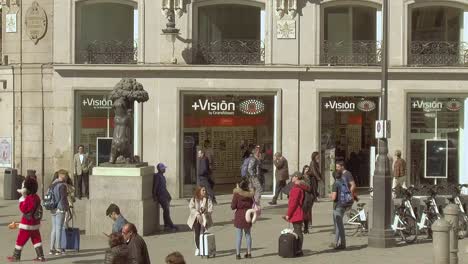 Puerta-del-Sol,-tourists-taking-photo-with-the-symbol-of-Madrid---statue-of-bear-and-strawberry-tree,-wide-shot