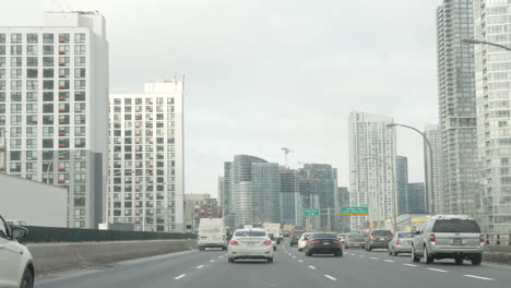POV-shot-driving-along-the-Gardiner-Expressway-in-Toronto,-with-moderate-traffic-and-condo-buildings-on-both-sides