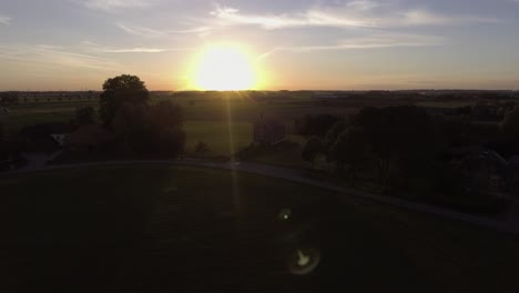 A-drone-shot-flying-to-the-left,-with-the-sun-going-down-behind-a-church