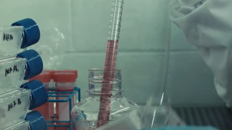 Pharmaceutical-lab-removing-cap-of-bottle-and-transferring-red-liquid-to-petri-dish