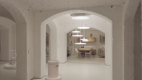 white-design-basement-with-minimalist-decoration-and-arches,-shot-moving-from-behind-a-pillar-to-the-room-and-pulling-focus