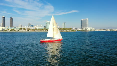 Red-sailboat-on-the-San-Diego-Bay-with-a-view-of-San-Diego's-skyline