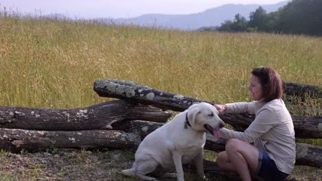 Woman-plays-with-White-Labrador-Retriever-with-mountain-backdrop