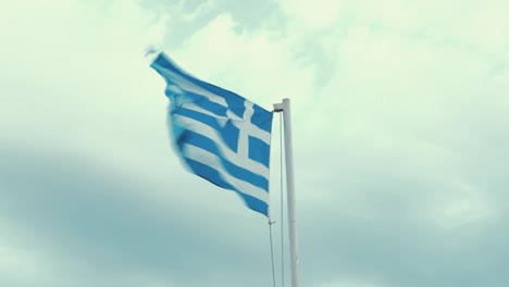 Abgenutzte-Griechische-Flagge,-Die-Im-Wind-In-Echtzeit-Weht,-Bewölkter-Himmel