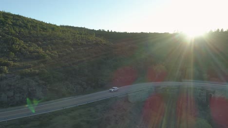 Aerial-of-car-driving-through-the-mountains-on-scenic-curvy-routewith-people-waving-out-of-it