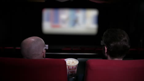 Two-men-share-popcorn-in-a-film-cinema-theatre