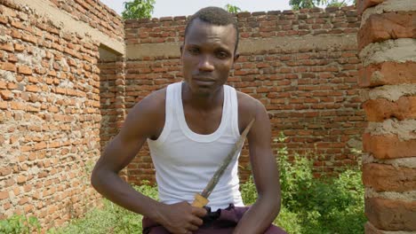 A-young-African-gangster-is-holding-a-knife-in-an-abandoned-building-in-rural-Africa