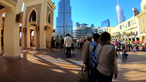 Zeitraffer-Für-Die-Souk-al-Bahar-Brücke-Vor-Dem-Dubai-Einkaufszentrum-Mit-Touristen,-Die-Vorbeigehen,-Den-Berühmten-Burj-Khalifa-Und-Den-Blick-Auf-Den-Brunnen-Fotografieren-Und-Genießen
