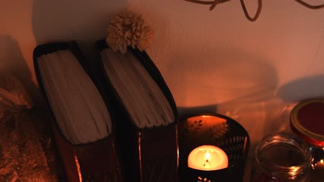 Relaxing-background-detail-shot-of-candles-with-flickering-flames,-some-herbs,-ancient-books-and-glass-jars
