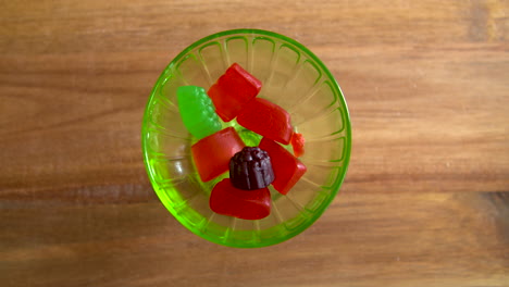 Top-down-shot-of-hands-taking-gummy-candies-out-of-a-glass-dish