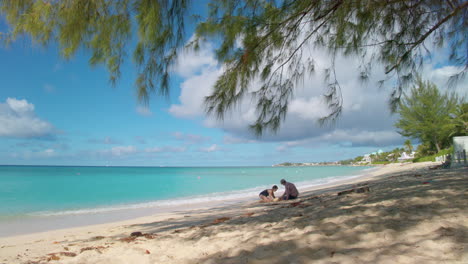 Grand-Cayman,-7-Mile-Beach,-Tilt-to-two-beachgoers