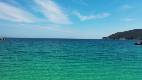 Playa-De-Arena-Vacía-Con-Agua-Azul-Turquesa-Cristalina-Junto-A-La-Costa-Mediterránea-En-Grecia