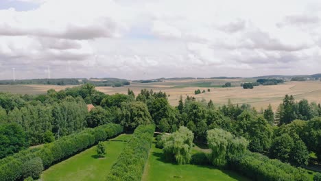 Aerial-shot-in-green-Park,-warmia-and-masuria-natural-place-with-green-grass-nad-tall-trees,-nice-clouds-on-the-sky